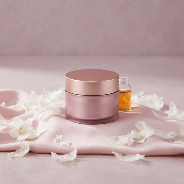 SS Medicube facial mask jar placed on blush pink fabric next to white flower petals and a glass vial.